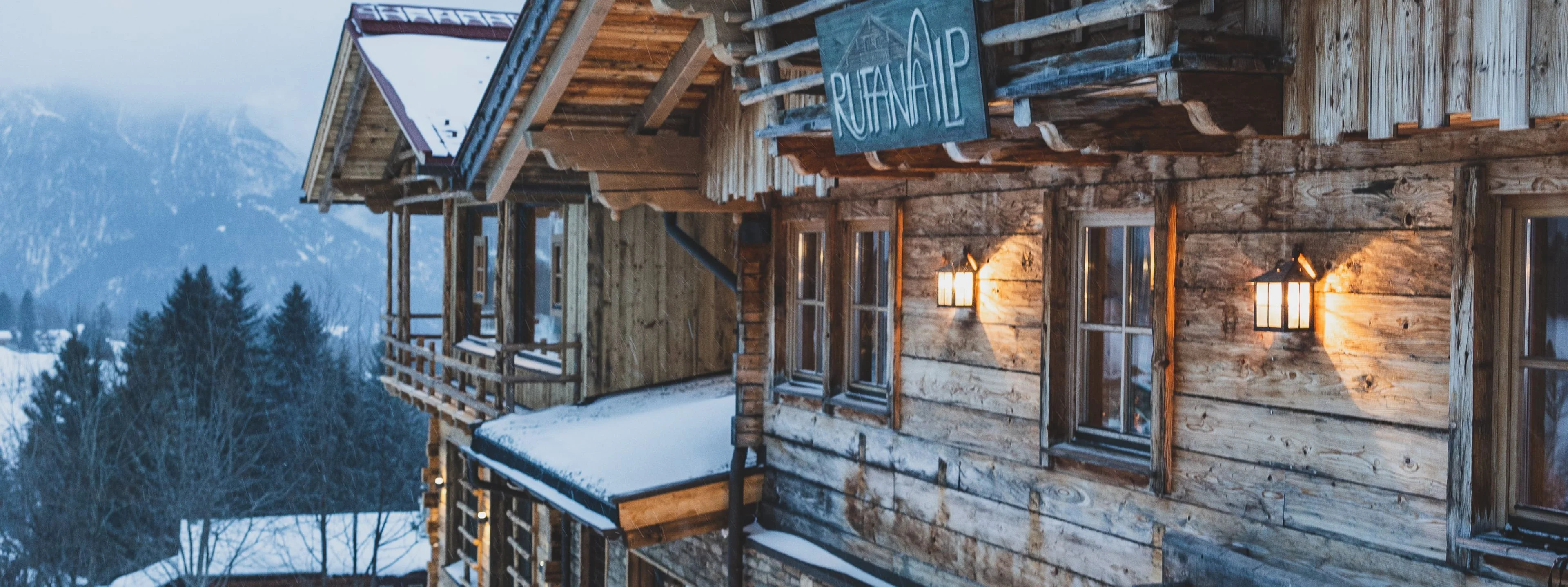 Die beleuchtete Holzfassade der Rufana Alp am Abend